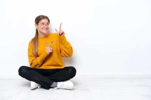 Mladý Běloška Žena Sedí Podlaze Izolované Bílém Pozadí Ukazuje Ukazováčkem — Stock fotografie