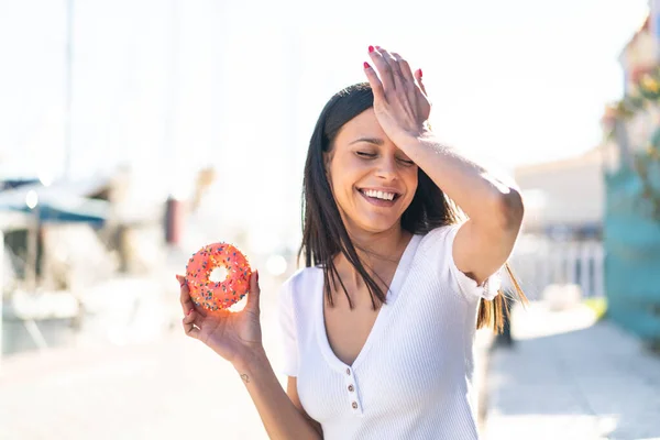 stock image Young woman at outdoors holding a donut at outdoors has realized something and intending the solution