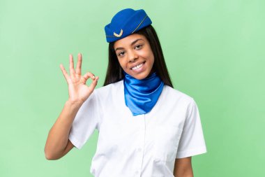 Uçak hostesi Afrikalı Amerikalı kadın izole edilmiş arka planda parmaklarıyla tamam işareti gösteriyor.