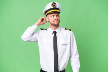 Uçak pilotu izole edilmiş arka planda kuşkuları ve kafa karıştırıcı yüz ifadesi var.