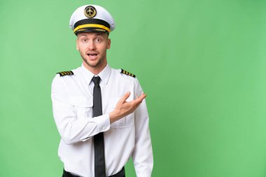 Uçak pilotu izole edilmiş arka planda şaşırmış ve işaret ediyor.