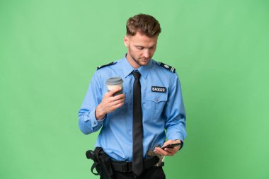Arka planda izole edilmiş genç bir polis kahve ve bir cep telefonu tutuyor.