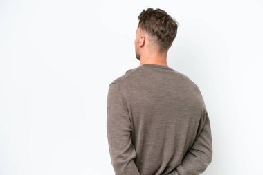 Beyaz arka planda izole edilmiş genç sarışın beyaz adam arkasına bakıyor.