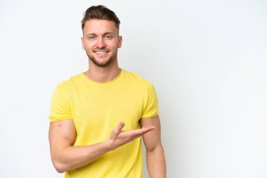 Beyaz arka planda izole genç sarışın beyaz adam bir fikir sunuyor ve gülümsüyor.