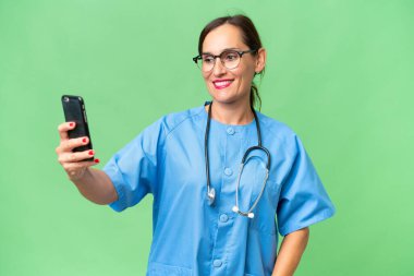 Tecrit edilmiş arka planda orta yaşlı hemşire bir kadın selfie çekiyor.