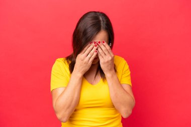 Orta yaşlı beyaz kadın, yorgun ve hasta bir ifadeyle kırmızı arka planda izole edilmiş.