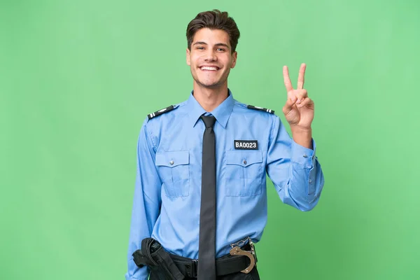 Молодий Поліцейський Над Ізольованим Тлом Посміхається Показує Знак Перемоги — стокове фото