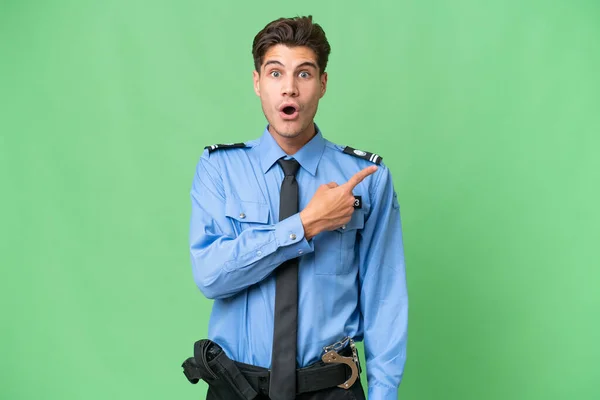 Молодий Поліцейський Над Ізольованим Тлом Здивований Вказує Сторону — стокове фото