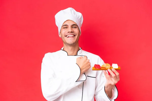 Joven Chef Caucásico Sosteniendo Sashimi Aislado Sobre Fondo Rojo Celebrando — Foto de Stock