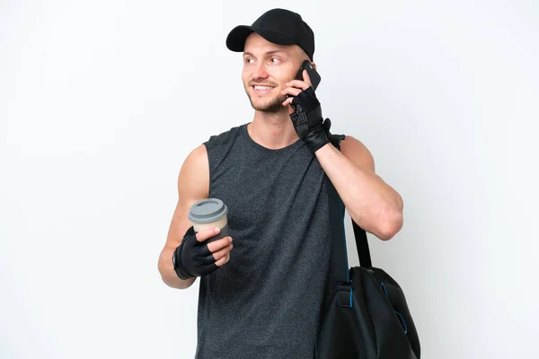 年轻的金发碧眼的白人男子 背着运动包 独立的白色背景 手里拿着咖啡和手机 — 图库照片