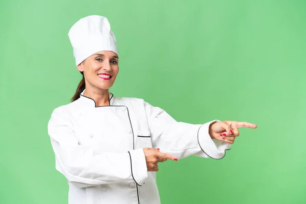 Middle Aged Chef Woman Isolated Background Pointing Finger Side Presenting — Stock Photo, Image
