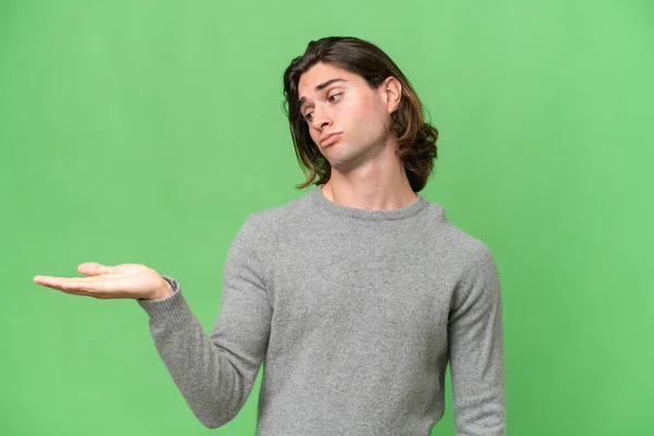 Young Caucasian Man Isolated Green Chroma Background Holding Copyspace Doubts — Stock Photo, Image