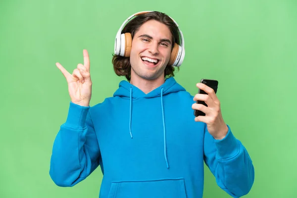 Jonge Knappe Man Geïsoleerd Groene Chroma Achtergrond Luisteren Muziek Met — Stockfoto