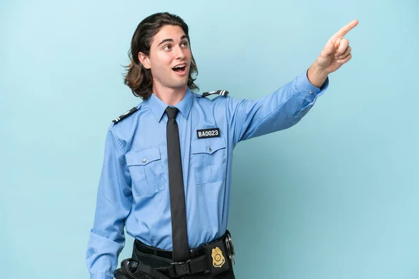 Молодий Поліцейський Білий Чоловік Ізольований Синьому Фоні Вказуючи Геть — стокове фото