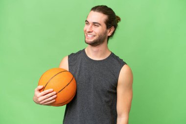 Genç basketbolcu, soyutlanmış arka planda yan tarafa bakıyor ve gülümsüyor.