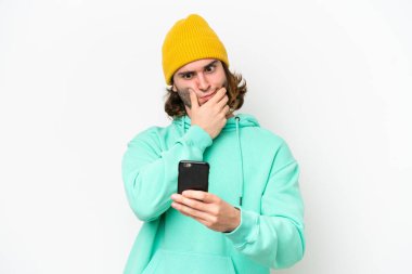 Genç yakışıklı adam beyaz krom arka planda izole edilmiş düşünüyor ve bir mesaj gönderiyor.