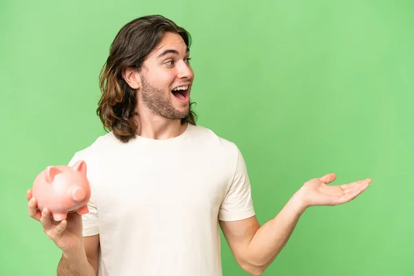 Young Handsome Man Holding Piggybank Isolated Background Surprise Facial Expression — Stock Photo, Image
