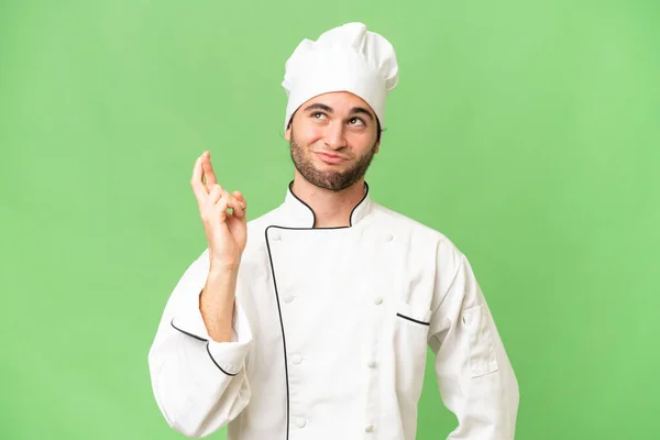 Jovem Bonito Chef Homem Sobre Isolado Fundo Com Dedos Cruzando — Fotografia de Stock