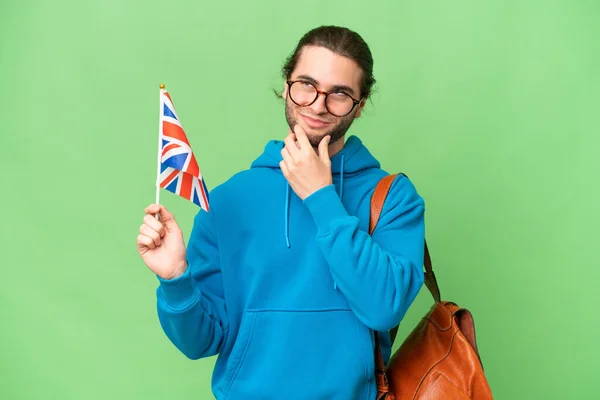 Młody Przystojny Mężczyzna Dzierżący Flagę Wielkiej Brytanii Odosobnionym Tle Patrząc — Zdjęcie stockowe