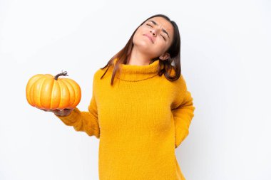 Beyaz arka planda balkabağı tutan beyaz bir kadın çaba sarf ettiği için sırt ağrısı çekiyor.