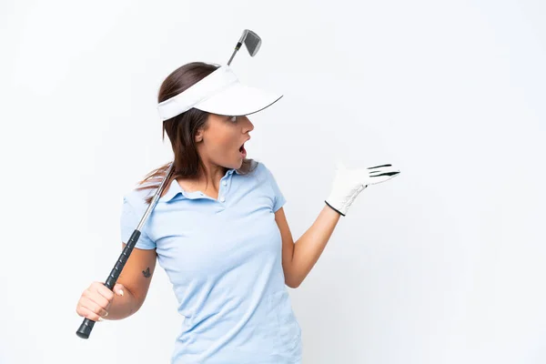 年轻的高加索女人在打高尔夫球时被白色背景隔离 她面带微笑地看着一边 — 图库照片
