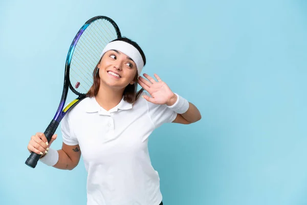Молода Тенісистка Ізольована Синьому Фоні Слухаючи Щось Поклавши Руку Вухо — стокове фото