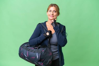 Spor çantalı orta yaşlı bir kadın izole edilmiş arka planda bir fikri düşünürken yukarı bakıyor.