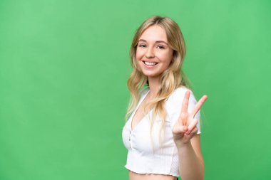 Genç İngiliz kadın izole edilmiş arka planda gülümsüyor ve zafer işareti gösteriyor.