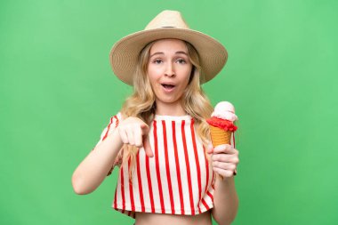 Kornet dondurması olan genç bir İngiliz kadın izole edilmiş arka planda şaşırmış ve ön tarafı işaret ediyor.