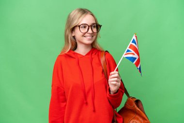 Birleşik Krallık bayrağını tutan genç İspanyol kadın izole bir arka planda yan tarafa bakıyor ve gülümsüyor.