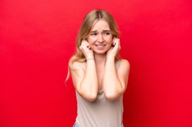 Young English woman isolated on red background frustrated and covering ears