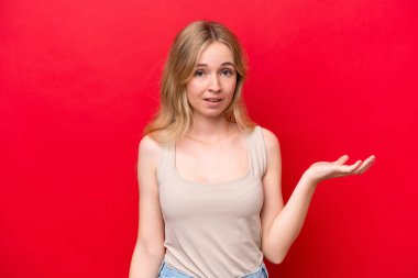 Kırmızı arka planda izole edilmiş genç bir İngiliz kadın şüpheli hareketler yapıyor.