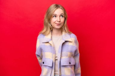 Young English woman isolated on red background and looking up