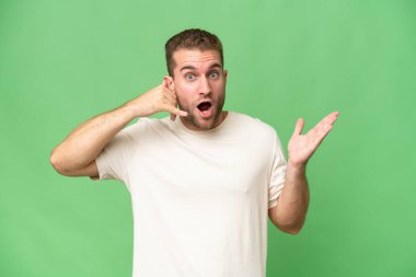 Genç beyaz adam yeşil krom arka planda izole edilmiş telefon jestleri yapıyor ve şüpheli.