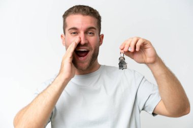Beyaz arka planda izole edilmiş ev anahtarlarını tutan beyaz bir adam bir şeyler fısıldıyor.