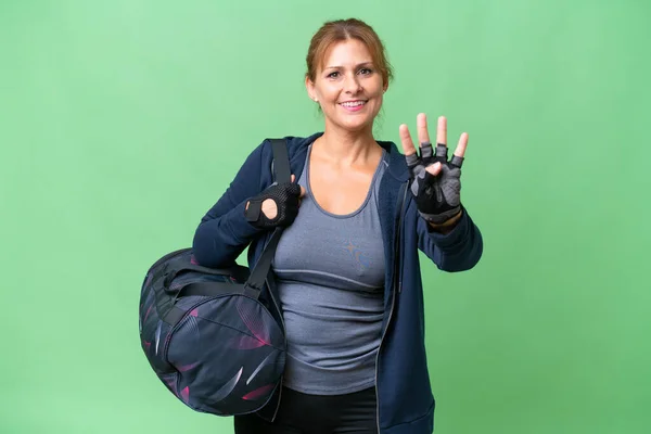 Middle-aged sport woman with sport bag over isolated background happy and counting four with fingers