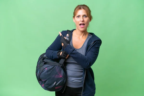中年スポーツ女性とともにスポーツバッグ上の隔離された背景驚きと指摘側 — ストック写真