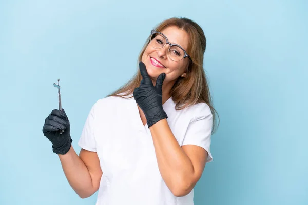 Zahnarzt Mittleren Alters Hält Werkzeuge Über Isolierten Blauen Hintergrund Glücklich — Stockfoto