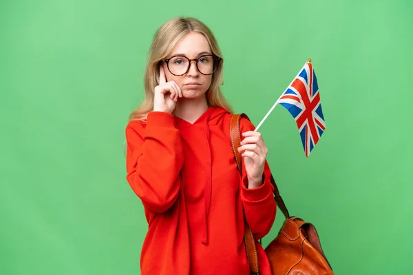 一个年轻的惊慌失措的女人举着英国国旗 在与世隔绝的背景下思考着一个想法 — 图库照片