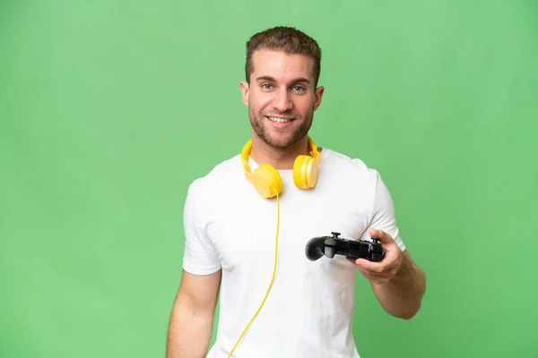 Νεαρός Όμορφος Άνδρας Παίζει Ένα Χειριστήριο Βιντεοπαιχνιδιών Απομονωμένο Πράσινο Φόντο — Φωτογραφία Αρχείου