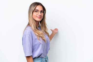 Genç Uruguaylı kadın, beyaz arka planda izole edilmiş, davet edilmek için ellerini yana uzatıyor.
