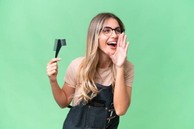 Genç Uruguaylı kuaför kadın izole arka planda ağzı sonuna kadar açık bağırıyor.