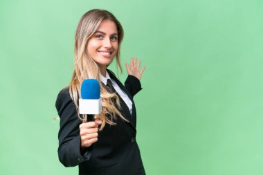 Genç, güzel Uruguaylı televizyon sunucusu izole edilmiş arka planda davet edilmek için ellerini yana uzatıyor.