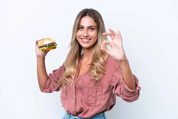 Młoda Ładna Urugwajska Kobieta Trzyma Hamburgera Odizolowany Białym Tle Pokazując — Zdjęcie stockowe