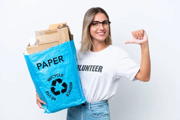 若いかなりウルグアイの女性は 誇りと自己満足白クロマの背景に隔離されたリサイクルのための紙でいっぱいのリサイクルバッグを持っています — ストック写真