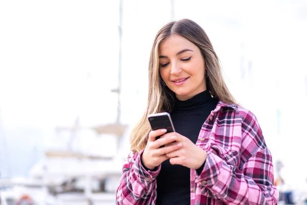 stock image Young pretty Romanian woman at outdoors sending a message or email with the mobile