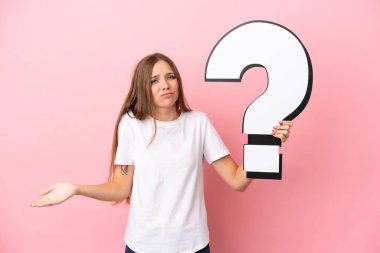 Pembe arka planda izole edilmiş genç Litvanyalı kadın elinde soru işareti simgesi tutuyor ve şüpheleri var.