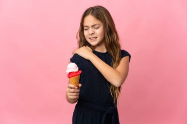Kornet dondurması ile izole edilmiş pembe arka planı olan çocuk çabaladığı için omuz ağrısından muzdarip.
