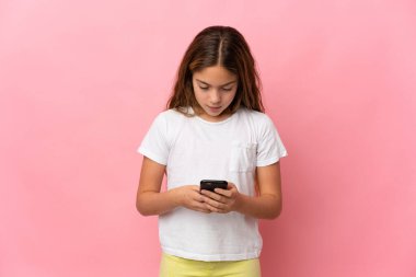 Child over isolated pink background using mobile phone