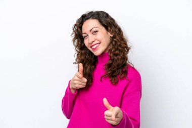 Beyaz arka planda izole edilmiş genç beyaz kadın şaşırmış ve ön tarafı işaret ediyor.